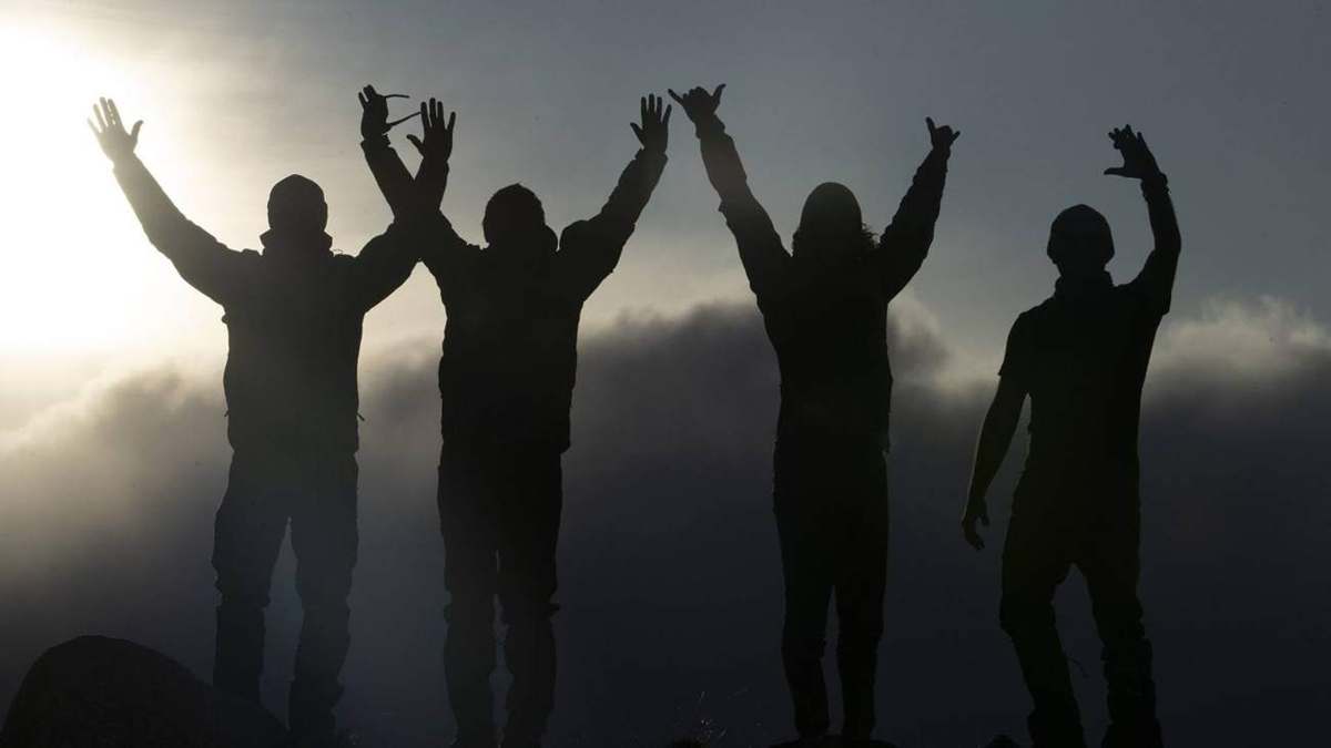 Siluetas de un equipo celebrando en la cima