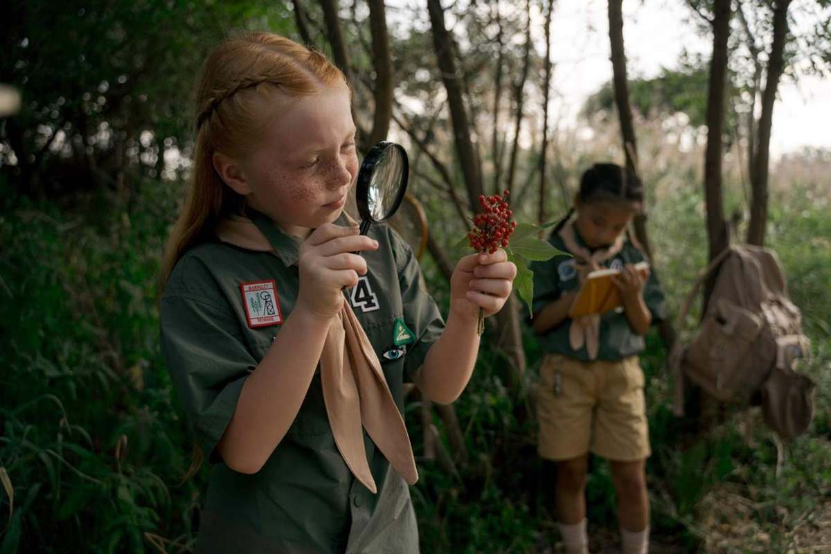Niña observando una flor con lupa